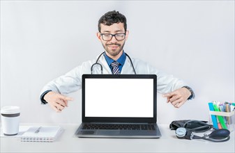 Handsome doctor pointing at an advertisement on the laptop screen