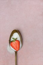 Spoon with sugar and halved strawberry