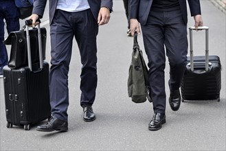Businessmen with rolling suitcases