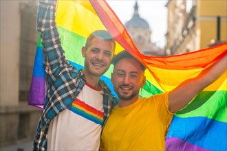 Portrait of gay male couple with rainbow flag at pride party in the city