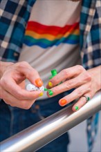 Attractive gay man painting his nails makeup with rainbow lgbt flag in the city