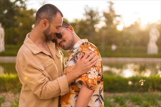 Homosexual couple embracing smiling at sunset in a park in the city