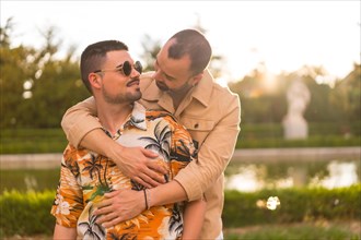 Homosexual couple embracing smiling at sunset in a park in the city