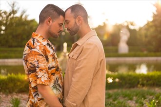 Romantic portrait of homosexual couple embracing at sunset in a park in the city