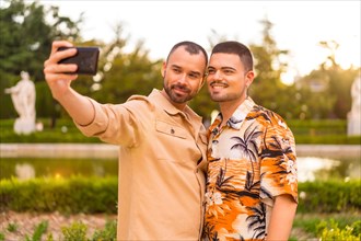 Homosexual couple taking a selfie at sunset in a park in the city