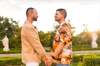 Romantic portrait of gay couple looking at each other at sunset in a park in the city