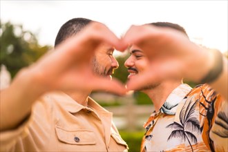 Portrait of gay boyfriend and girlfriend making heart or love gesture at sunset in a park in the city