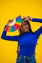 Portrait of a black ethnic woman with a rainbow lgbt fan on a yellow background