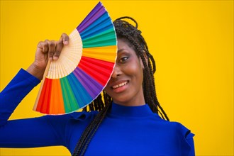 A black ethnic woman with a rainbow lgbt fan on a yellow background
