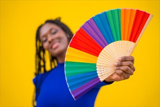 Lgbt rainbow fan and an attractive black ethnic woman on a yellow background