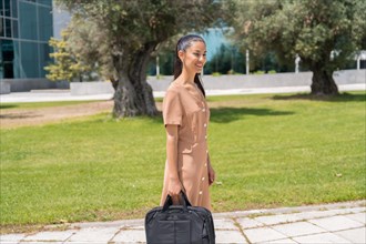 Latin woman executive or businesswoman walking with a briefcase with a computer