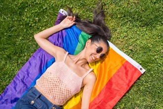Caucasian brunette woman with a rainbow lgbt flag on the grass