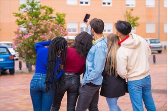 Group of multi ethnic friends walking through the university campus having fun taking a selfie