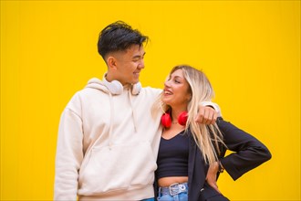 Portrait of a multi-ethnic couple of Asian man and Caucasian woman on a yellow background