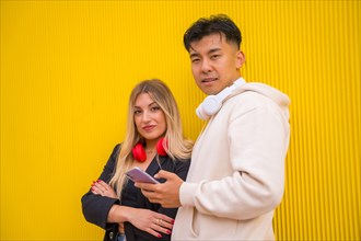 Portrait of multi-ethnic couple of Asian man and Caucasian woman on a yellow background
