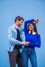 Multiethnic dancer couple of Caucasian man and black ethnic woman on a blue background having fun