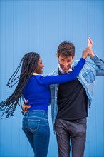 Multiethnic dancer couple of Caucasian man and black ethnic woman on a blue background having fun
