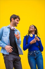 Multiethnic dancer couple of Caucasian man and black ethnic woman on a yellow background having fun
