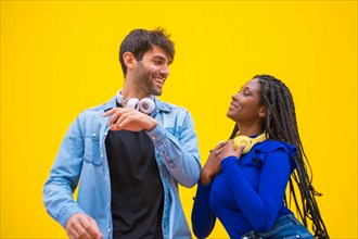 Multiethnic wedding couple of Caucasian man and woman of black ethnicity on a yellow background having fun