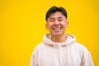 Portrait of a handsome Asian man in basic clothes smiling isolated over yellow background