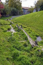 Spring with wooden water pipe in green meadow