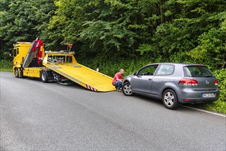 Defective VW Golf behind tow truck at roadside