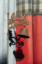 Two birds with a bell on a door