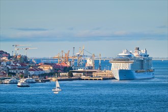 View of Lisbon over Tagus river from Almada with yachts tourist boats and cruise liner moored at cruise terminal at sunset