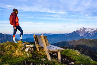 Mountaineer next to a wooden bench enjoying the view towards Hoher Göll