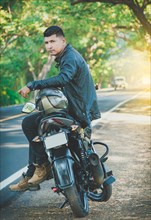 Portrait of biker in jacket sitting on his motorcycle at the side of the road