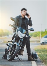 Handsome biker calling on the phone in the street