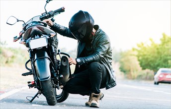 Motocyclist fixing the motorcycle on the road
