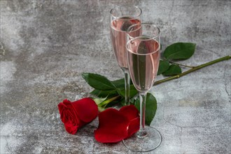 Two glasses of champagne and a rose on a white background and copy space valentine's day symbol