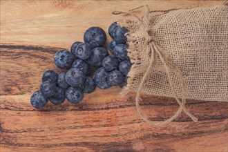 Fresh blueberries in a raffia bag on a wooden table