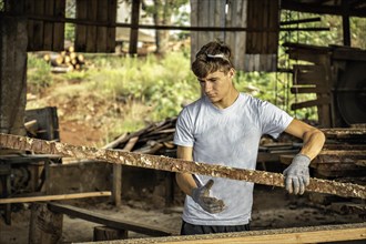 Young man working in a sawmill wearing protective gloves