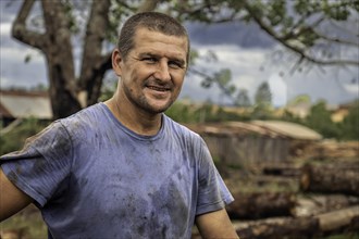 Close-up of a handsome man working in a sawmill smiling and looking at the camera