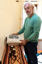 Older man with white hair and beard performing a diagnosis with a radionic machine