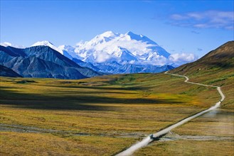 Road to Mount Denali in Alaska with a bus and snow capped mountain peak in autumn