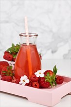 Red strawberry fruit lemonade in jar surrounded by berries