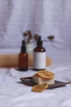 Essential oil bottles and organic vegan soap with dried lemon slices