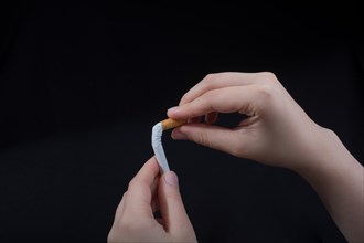 Hand is breaking a cigarette on a black background