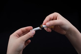Hand is breaking a cigarette on a black background