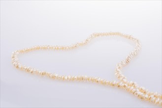 Pearl necklace is placed on white background