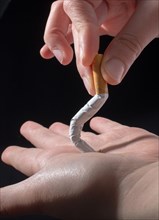 Hand is breaking a cigarette on a black background