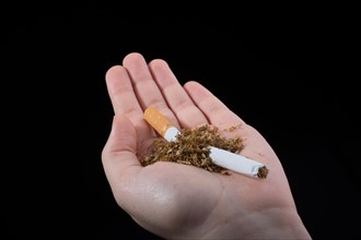 Hand is breaking a cigarette on a black background