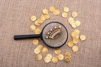 Crown under magnifying glass with fake gold coins