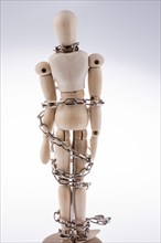 Wooden model man in chains on a white background