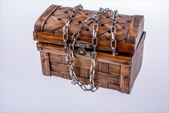Wooden brown treasure box in chains on a white background