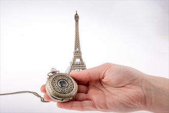 Hand holding a pocket watch befere Eifel Tower