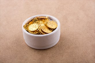Fake gold coins in white box on brown background